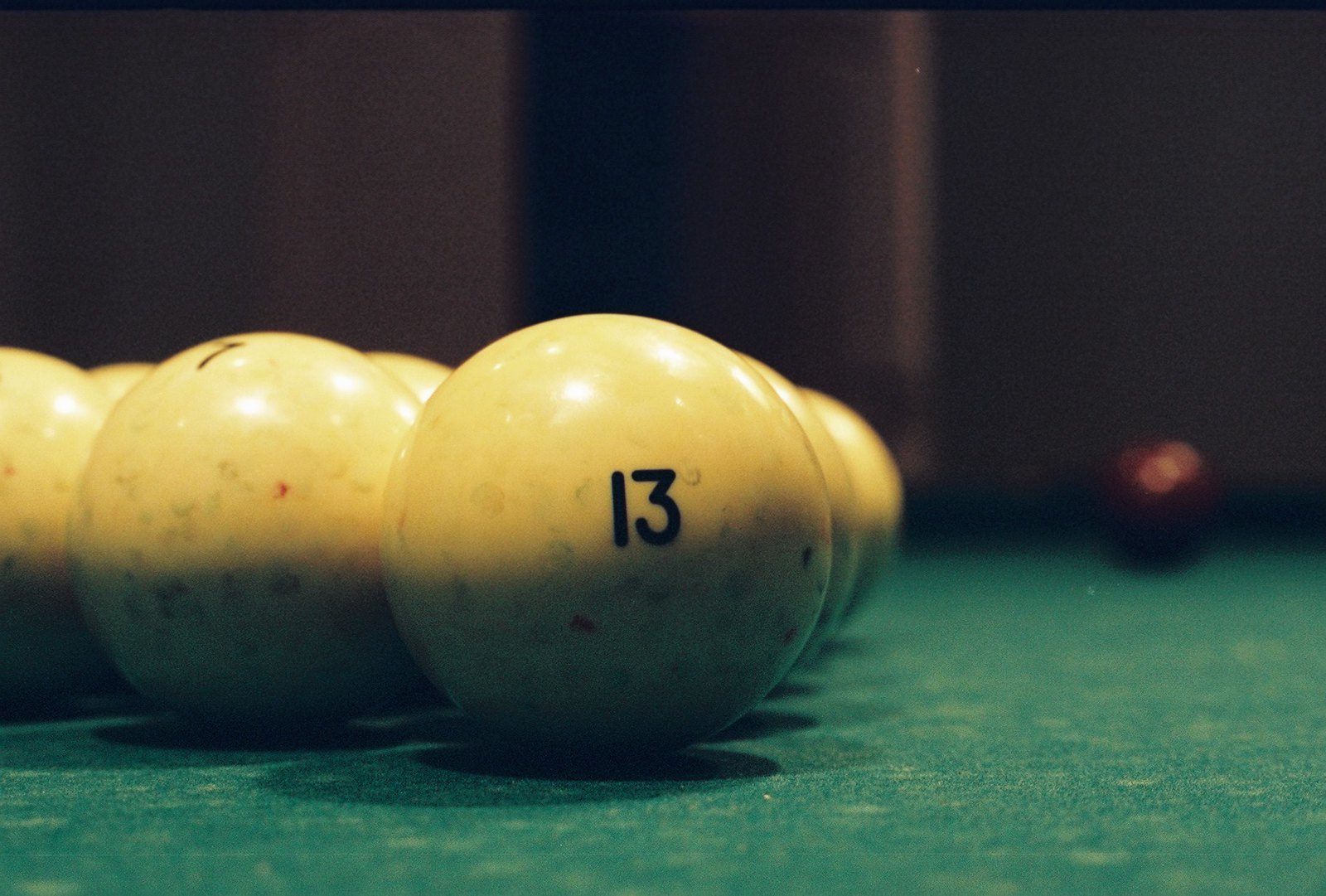 Billiards balls on a billiards table. In the foreground is a while ball showing the number 13.